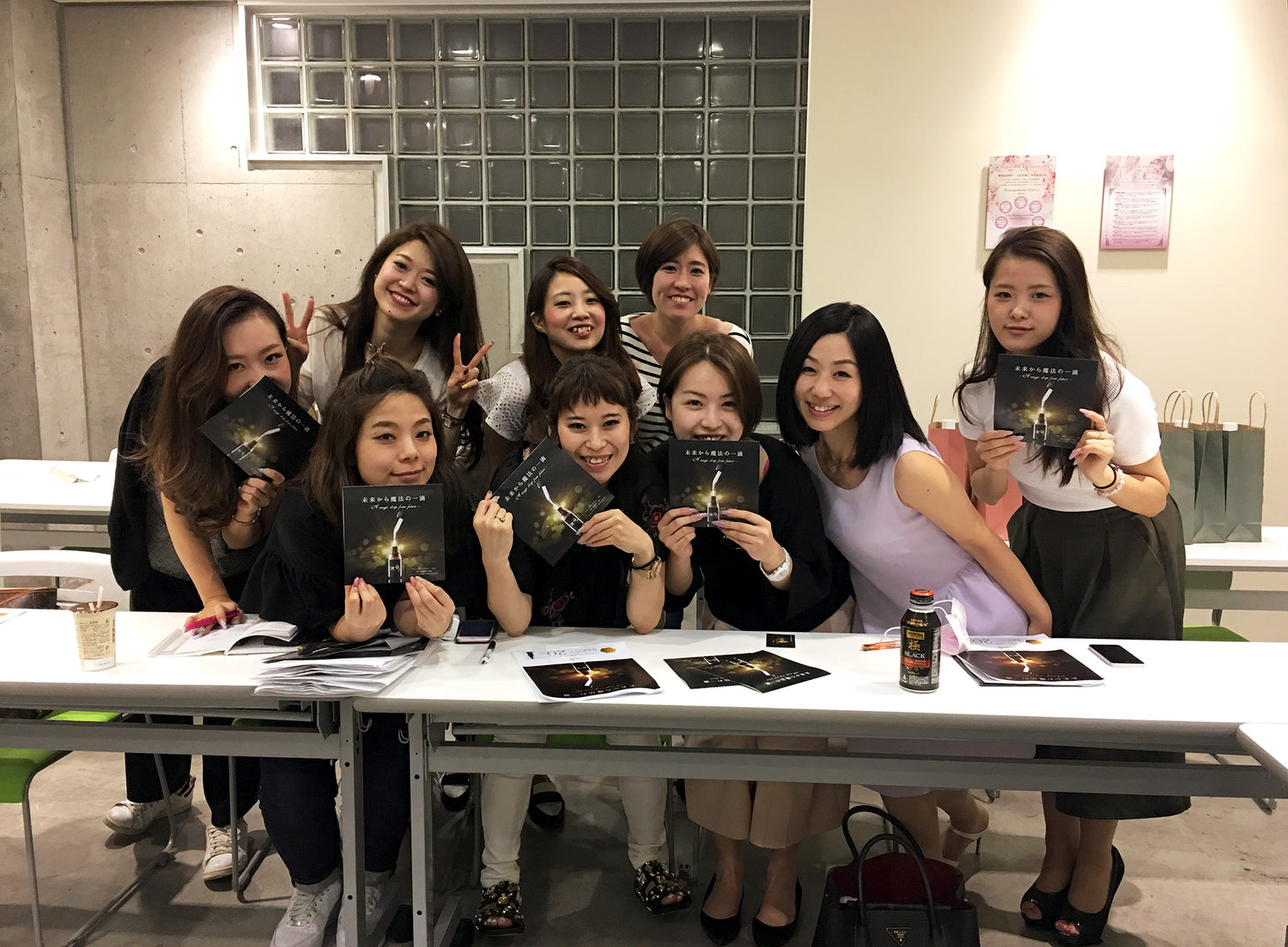 Majestic Cosme team members smiling behind a table, each holding Majestic Skin human stem cell serum brochures.